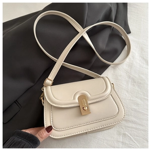 Detailed top view of a cream faux leather crossbody bag with a gold twist lock closure