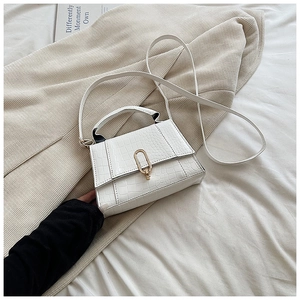 Gros plan d'un sac à main blanc motif crocodile en cuir PU avec boucle métallique dorée en U