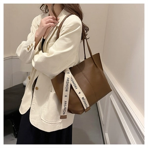 Detailed view of brown leather tote bag featuring a decorative fashion ribbon strap