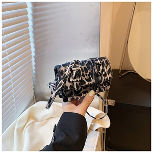 Close-up of leopard print crossbody bag with dual metal buckle straps and slim shoulder strap