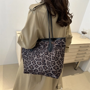 Grande borsa tote leopardata con cinturini in pelle nera abbinata a un trench chic
