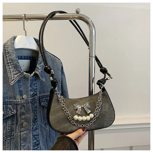Détail du sac bandoulière en denim gris avec nœud argenté et chaîne de perles