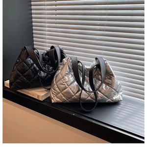 Detail of glossy quilted tote bags in black and silver colors with long shoulder straps