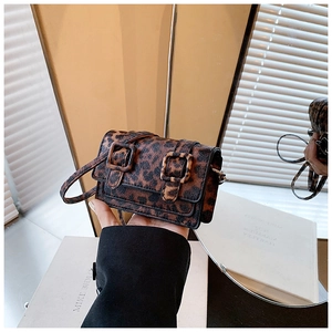 Detail of a mini leopard print crossbody bag with vintage buckle straps and textured finish