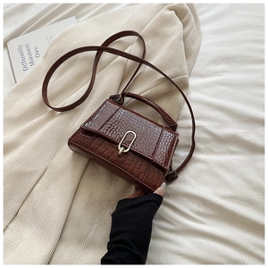 Détail de la texture croco et boucle dorée en U sur ce sac à main marron chic