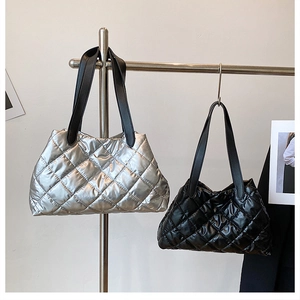 Detailed view of silver and black quilted tote bags on a modern chrome display stand
