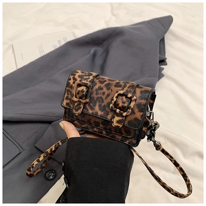 Detailed close-up of compact leopard print crossbody bag with dual buckles and slim strap