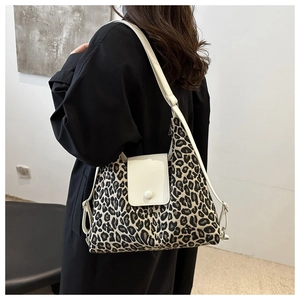 Leopard print tote bag with white flap and silver metal buckle worn by a model