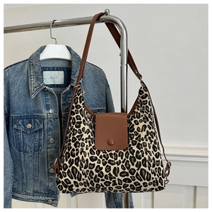 Detail of leopard print canvas tote bag with brown faux leather trim and metallic buckle