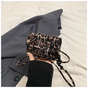 Detail of leopard print faux leather bag featuring double strap buckles and metal accents