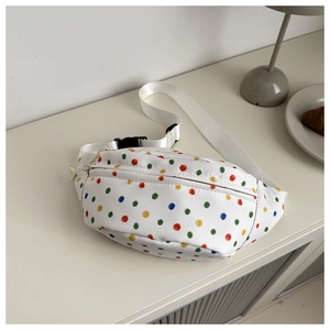 Close-up of a white polka dot fanny pack with colorful patterns on a minimalist desk