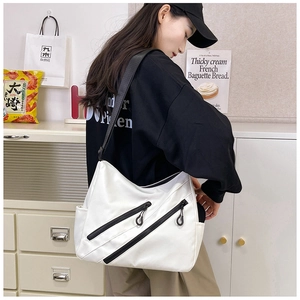 Detail of white nylon tote bag featuring parallel black zippers and adjustable strap