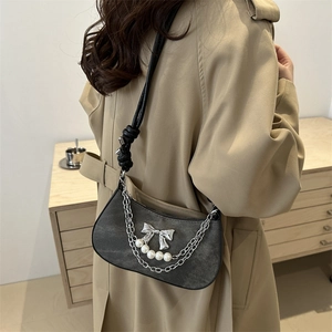 Sac bandoulière en denim gris avec nœud argenté et chaîne perlée porté par un mannequin