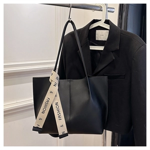 Detail of black leather tote bag with fashion letter ribbon hanging on a coat hanger