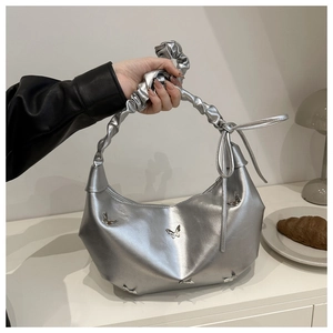 Détail du sac demi-lune argenté avec papillon métallique et poignée froncée élégante