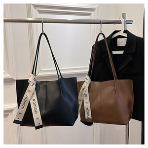 Detail view of large commuter tote bags in black and brown with decorative ribbons