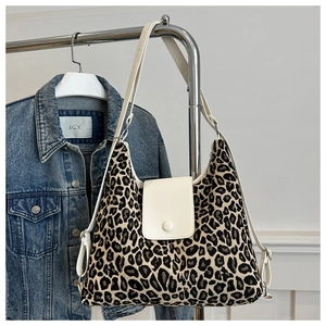 Detail view of leopard print shoulder bag with white leather flap and button closure