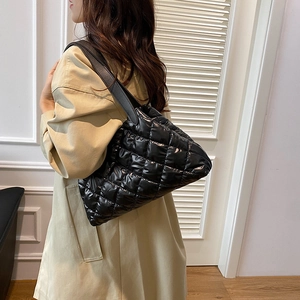 Quilted black puffer tote bag with wide shoulder strap for women in minimalist style