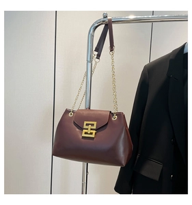 Detail of burgundy tote bag with gold geometric clasp and leather chain strap