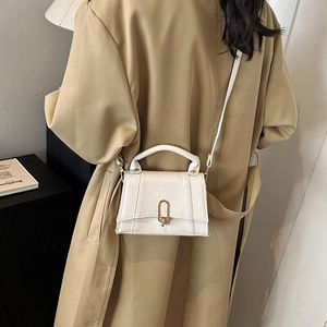 Sac à bandoulière blanc motif crocodile et fermoir doré porté sur un trench-coat