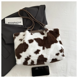Détail du cabas en peluche motif vache avec bandoulière en cuir sur blazer gris