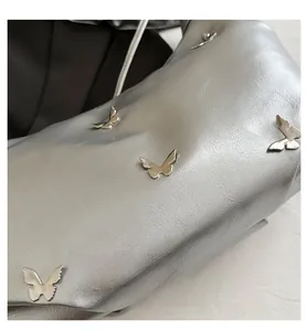 Gros plan sur un sac cabas argenté plissé avec ornements papillons en métal 3D