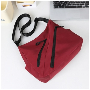 Detail view of burgundy nylon tote bag with functional diagonal zippers and strap