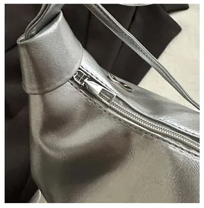 Détail de la fermeture éclair en métal argenté et texture cuir de ce sac fourre-tout