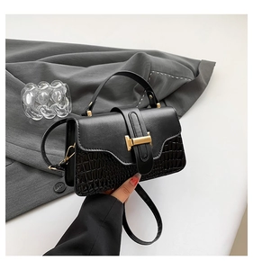 Close-up of black stone pattern leather bag with gold H-clasp on grey suit background