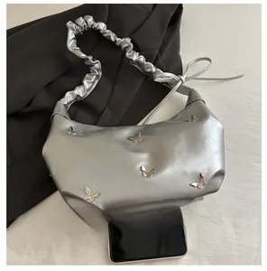 Détail du sac hobo métallisé argenté avec boucles papillon et bandoulière à volants