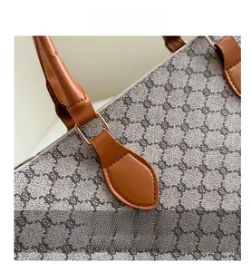Détail du cabas en toile monogramme vintage avec poignée en cuir marron et boucles dorées