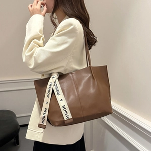 Brown large capacity tote bag with fashion ribbon detail on shoulder of a model