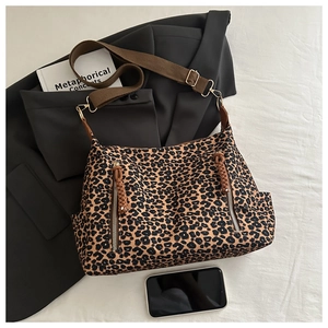 Close-up of leopard print tote bag with decorative zippers and adjustable strap on a blazer