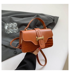 Detail of caramel crocodile pattern PU leather handbag with elegant gold metal twist lock