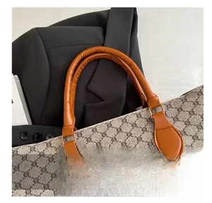 Détail du motif monogramme vintage et de la poignée en cuir caramel de haute qualité du sac