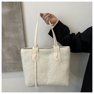 Close-up of white fleece tote bag with smooth leather straps and soft plush texture detail