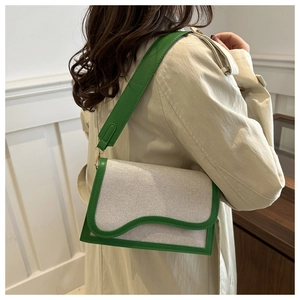 Detail of contrast stitch shoulder bag with green leather trim and wave flap design