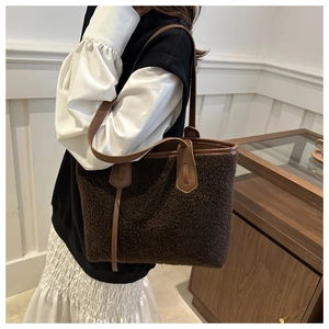 Close-up of fluffy dark brown faux shearling tote bag with premium caramel leather details