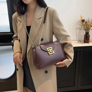 Deep burgundy leather tote bag with gold chain strap and geometric buckle on khaki coat