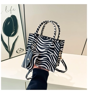 Detail shot of zebra print square bag featuring a mini pouch and adjustable strap