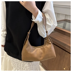 Detail of a brown faux suede tote bag with pleated texture on an indoor model