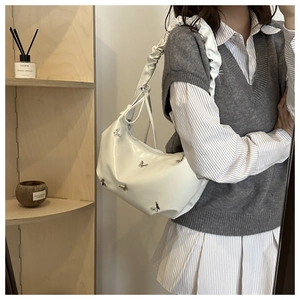 Détail du sac à bandoulière blanc froncé orné de papillons argentés sur un modèle
