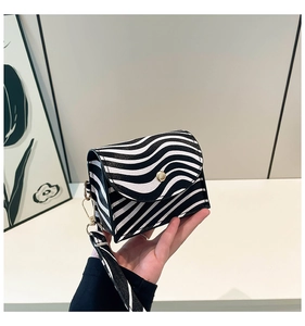 Close-up of zebra pattern mini handbag with gold twist lock and matching wide strap
