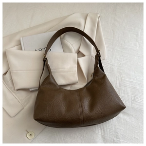 Detail of dark brown faux suede crescent bag with textured leather and stitching