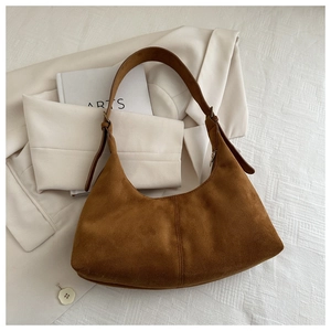 Close-up of caramel suede hobo bag texture and adjustable strap on a minimalist blazer