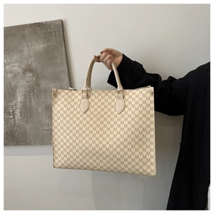 Détail du sac cabas beige vintage avec motif M porté par un mannequin pour le quotidien