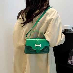 Green leather handbag with stone texture and metallic H buckle shown in lifestyle setting