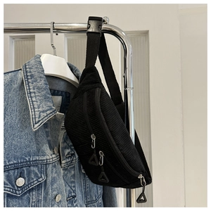 Detail of classic black corduroy waist bag with textured fabric and dual zippers
