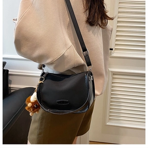 Detail of black saddle bag with adjustable strap and cute brown lion plush charm
