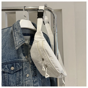 Detail of white corduroy fanny pack with texture, double zippers and buckle on denim jacket